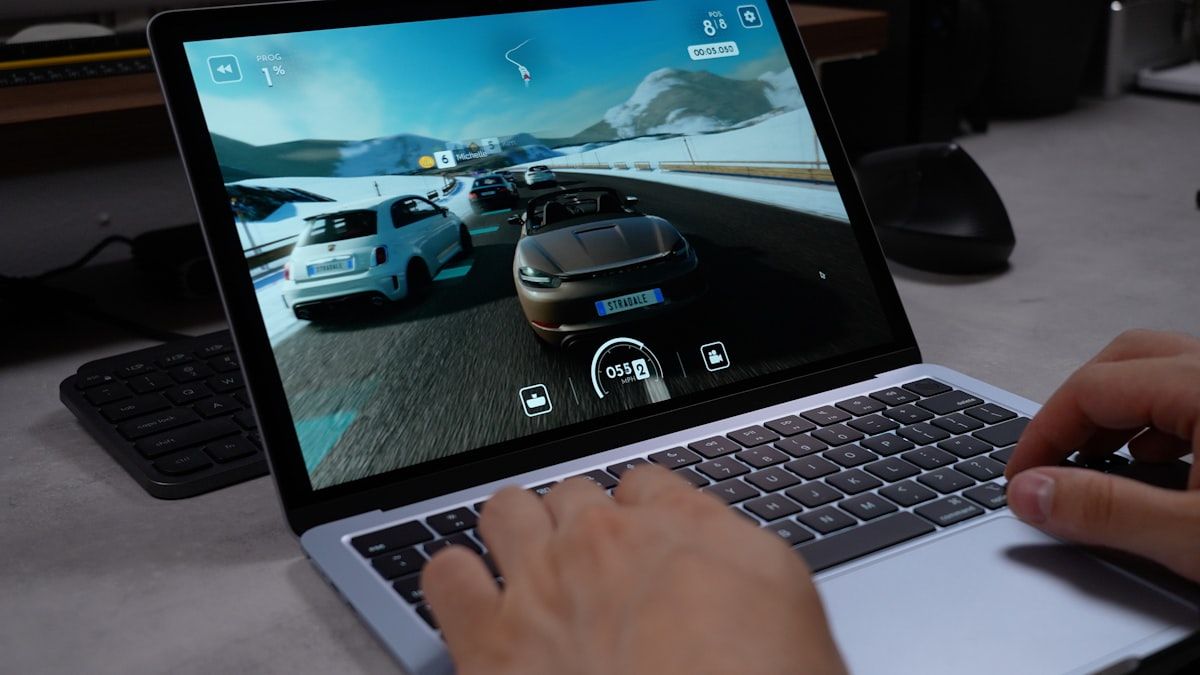 Jogador se divertindo com jogo de corrida em laptop Jogador concentrado jogando um jogo de corrida em um laptop moderno